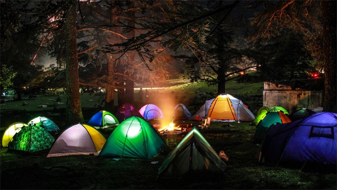 Magical night camping in Europe with tents glowing under lantern lights in a quiet forest setting