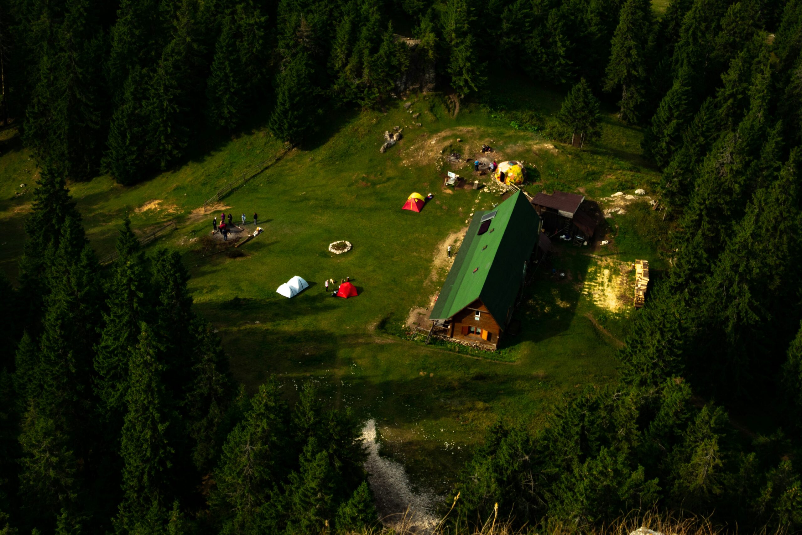 Aerial view of a forest camping site in Slovenia with colorful tents on a green meadow – one of the best camping sites in Europe