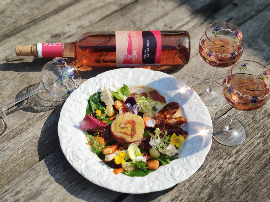 Traditional Serbian food in modern Vinarium vinery and rosé wine on a rustic wooden table
