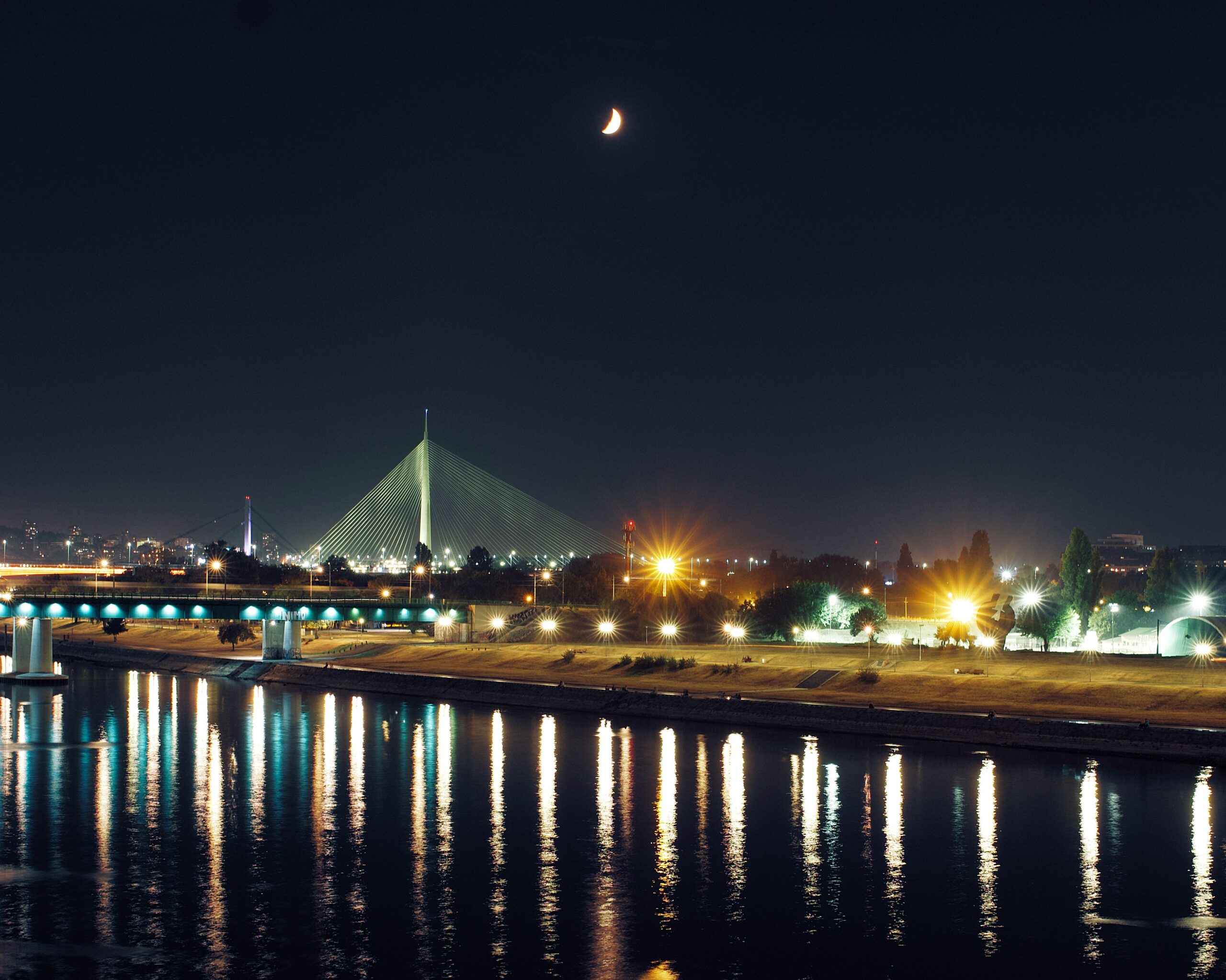 Night view of Ada Bridge in Belgrade with moonlight and reflections on the Sava River