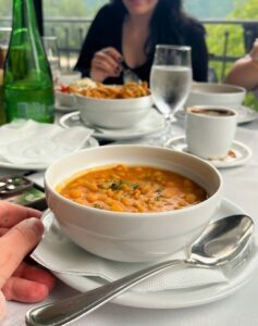 Serbian bean stew (pasulj) served in a white bowl, accompanied by traditional black coffee and sparkling water – typical Serbian comfort food